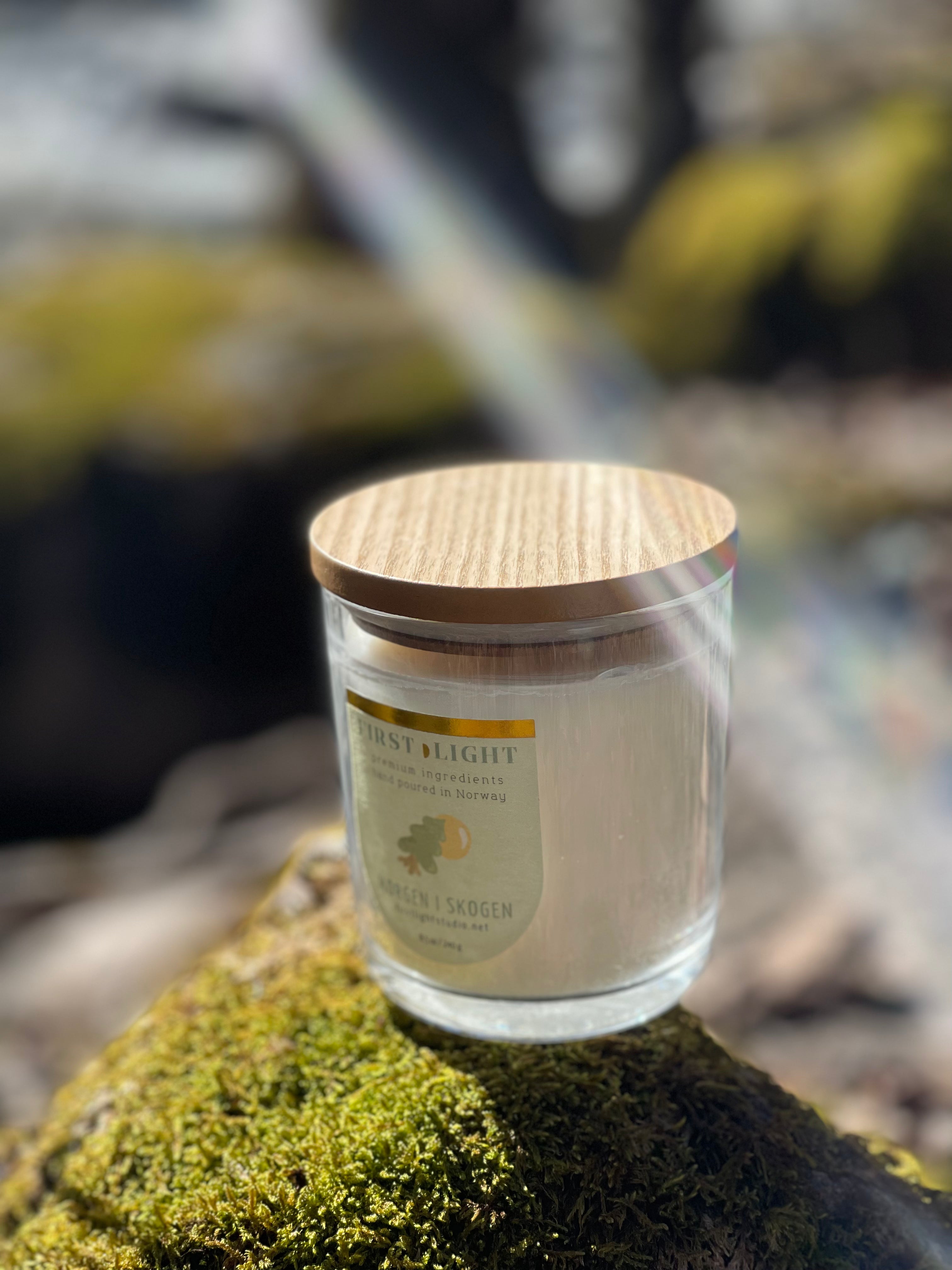 Candle jar with wooden lid on a mossy rock with a blurred natural background