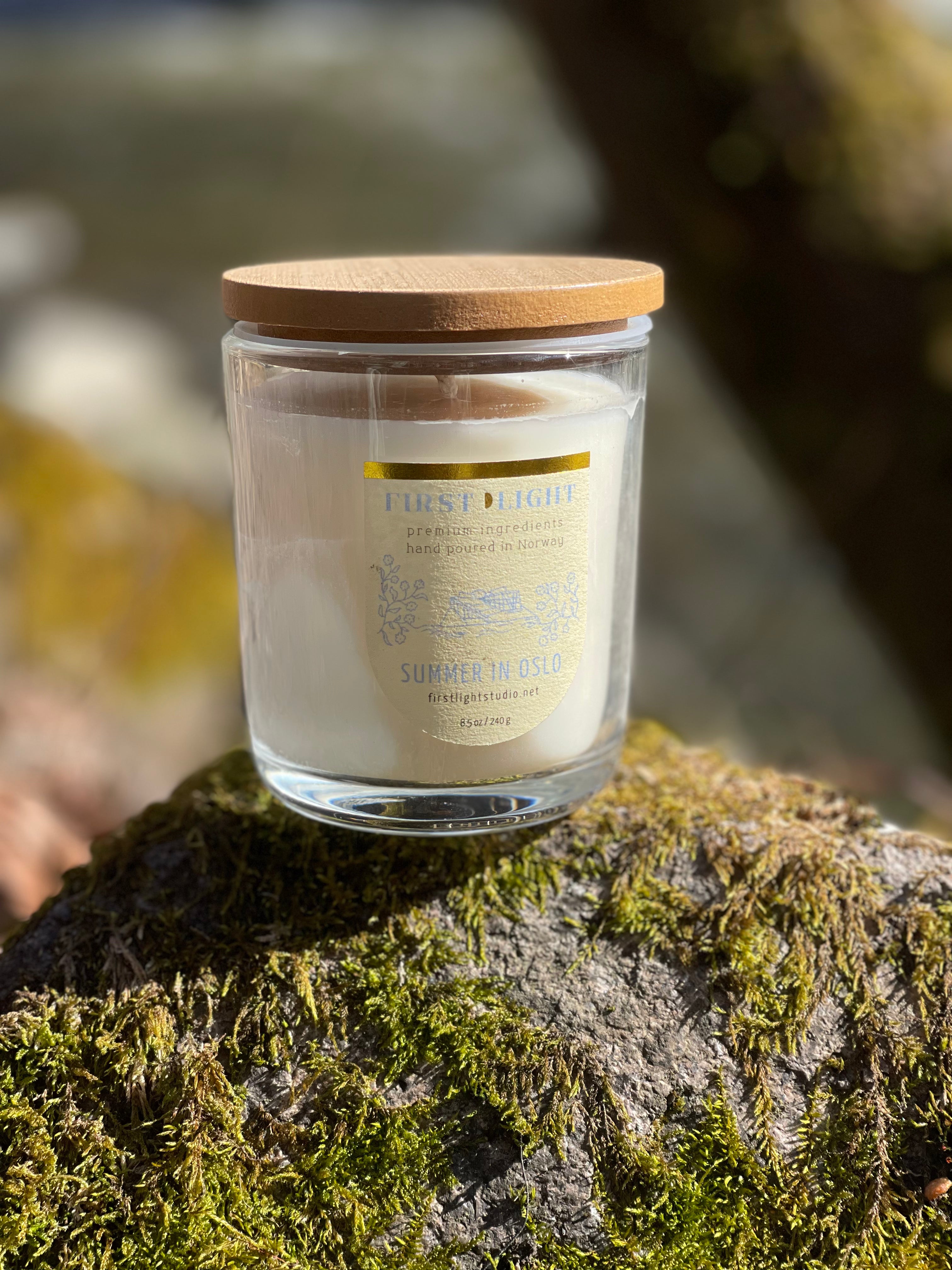 Candle in a glass jar with a wooden lid on a mossy surface