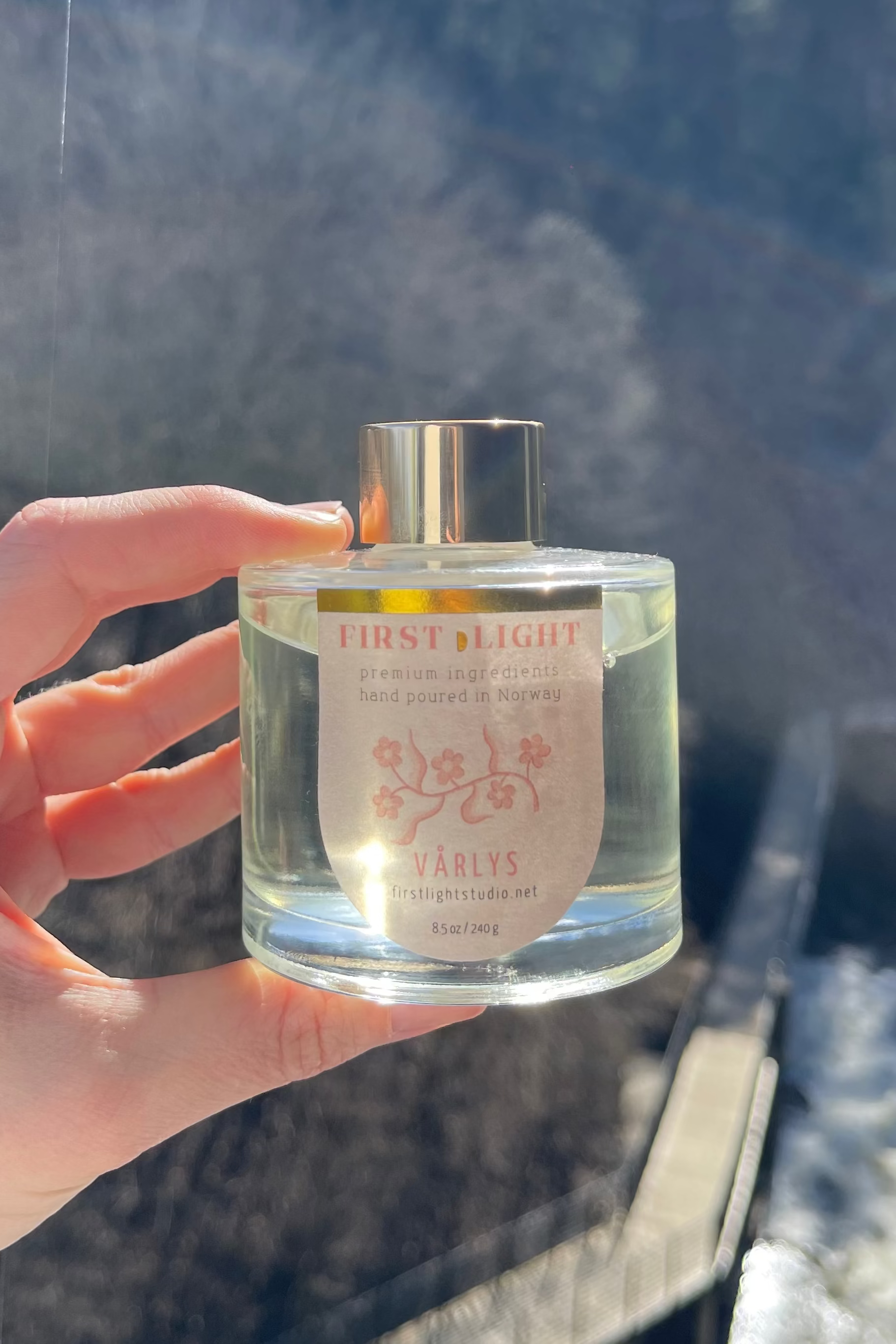 Hand holding a bottle of 'Fruit & Flower' perfume with a scenic background
